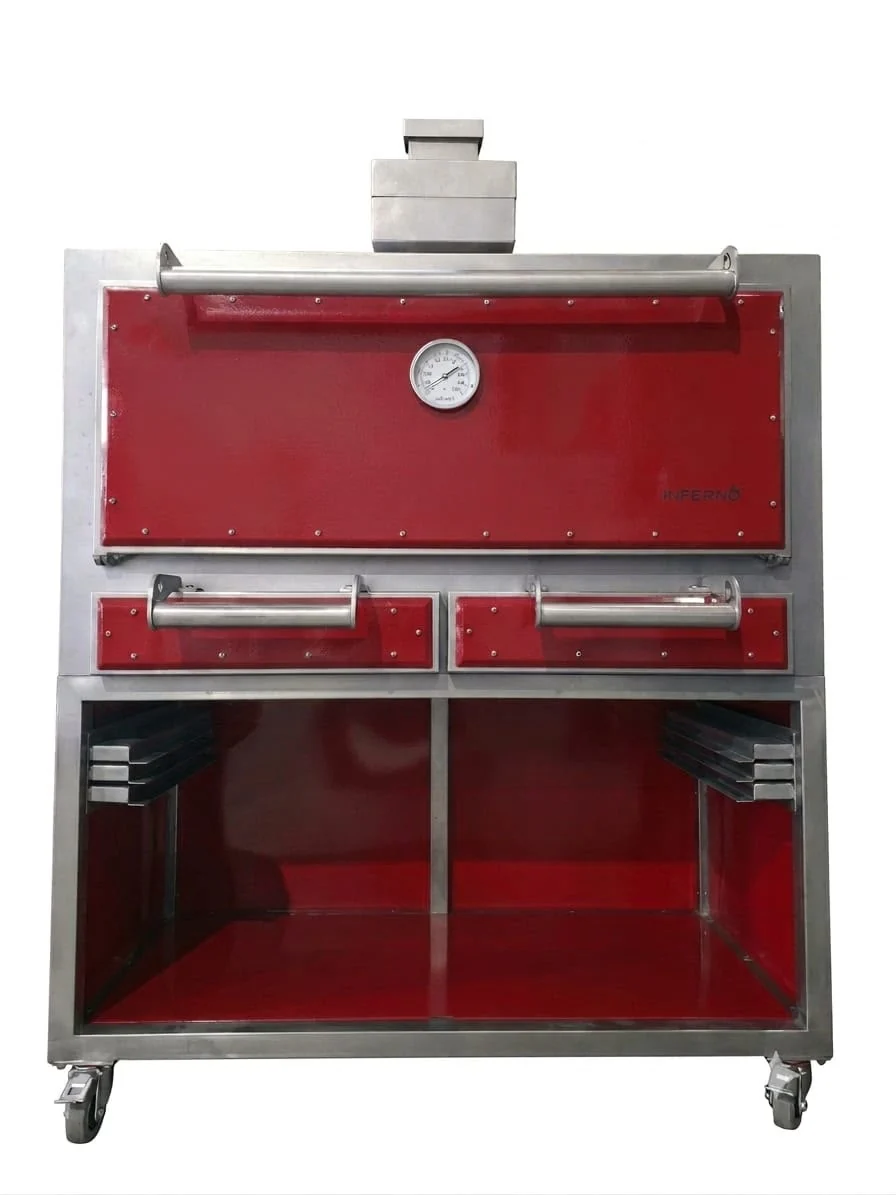 The Inferno 1200 from the front on its stand: a red door with a thermometer over two red drawers, the stepped chimney on top, and a divided red-lined stand with grid storage at each side, on castors.